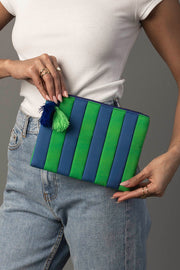 A person in a white top and jeans holds the Panache Apparel Collection Blue & Green Striped Clutch, which features a green and blue tassel.