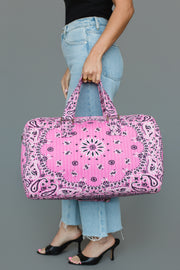 A person in blue jeans and black heels holds the Panache Apparel Collection Pink Bandana Duffel against a plain gray background.