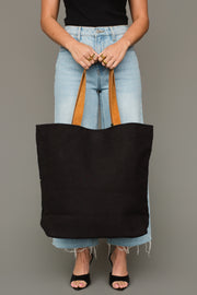 A person wearing a black sleeveless top, light blue jeans, and black heels holds the Panache Apparel Collection Black, Olive, Gray & Cream Western Tote in front of them against a plain background.