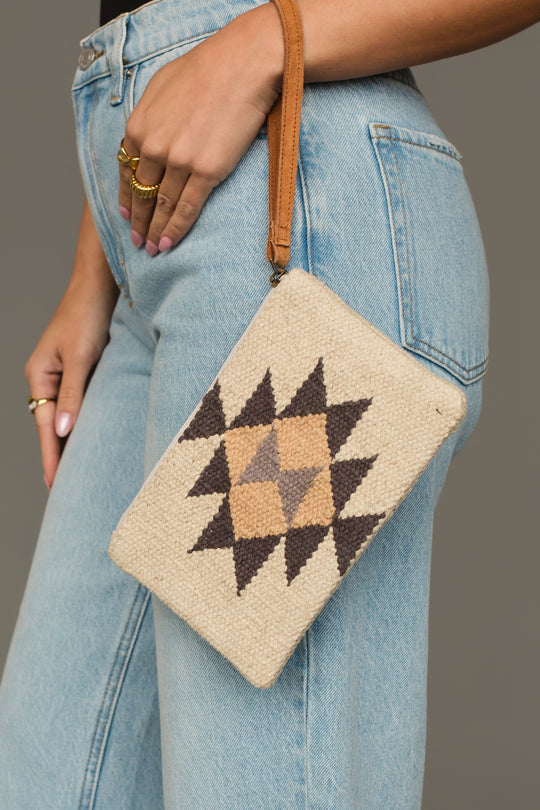 A person wearing blue jeans holds the Panache Apparel Collection Khaki, Gray & Tan Western Wristlet.