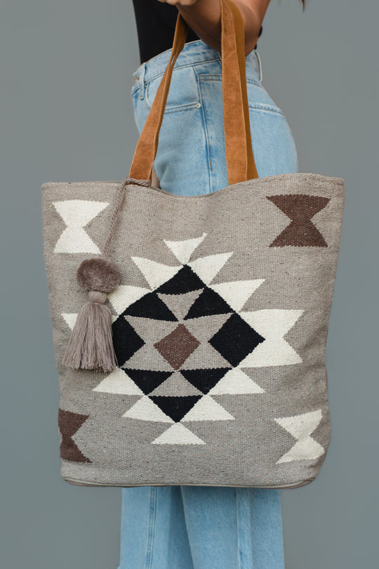 A person holds the Panache Apparel Collection Taupe, Cream, Brown & Black Western Tote, which features geometric patterns, a tassel accent, and brown handles.