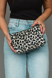 A person in light blue jeans and a black top holds the Panache Apparel Collection Black, Cream & Blue Leopard Travel Pouch.