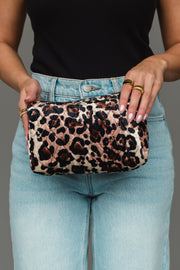 A person wearing a black top and light blue jeans holds the Panache Apparel Collection Brown & Cream Leopard Travel Pouch with both hands, displaying rings on their fingers.