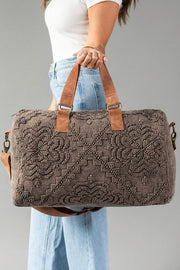 A woman in a white top and blue jeans holds the Panache Apparel Collection Brown Vintage Inspired Textured Duffel against a plain gray background.