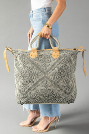 A person in light blue jeans and heels holds the Gray Vintage Inspired Textured Tote by Panache Apparel Collection, featuring suede leather handles, tan accents, an intricate pattern, and a secure top zipper.