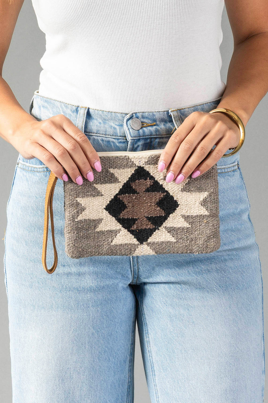 A person in light blue jeans and a white top holds the Panache Apparel Collection’s Taupe, Cream, Brown & Black Western Wristlet.