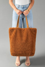 A person stands against a plain gray background holding the Panache Apparel Collection’s Orange, Cream & Pink Western Tote. They wear light blue jeans, a white top, sandals, and a gold bracelet.
