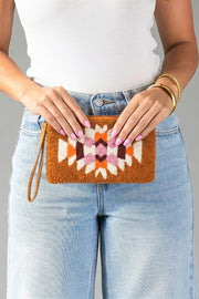 A person in a white tank top and light blue jeans holds the Panache Apparel Collection Orange, Cream & Pink Western Wristlet.