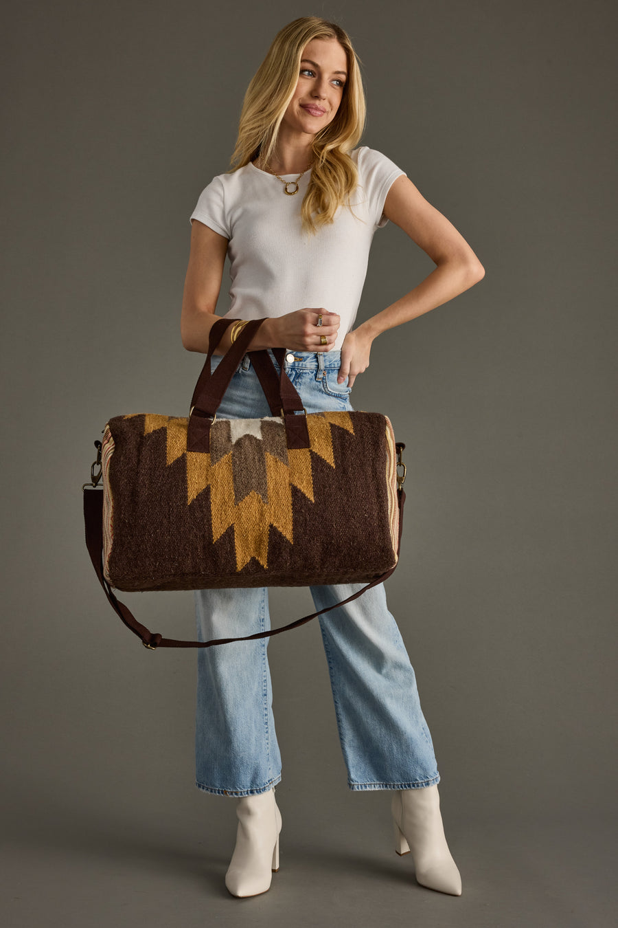 Woman holding a brown and yellow patterned bag against a gray background
