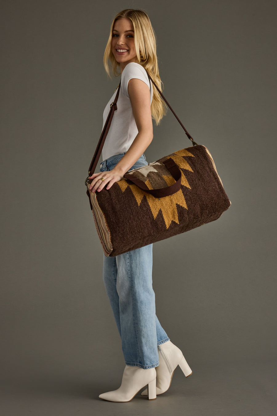 Woman holding a brown bag with a decorative element against a gray background