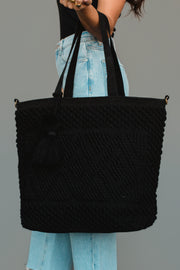 A woman in light blue jeans and a black top holds the Panache Apparel Collection Black Diamond Pattern Textured Tote, featuring tassel detailing and matching black straps.