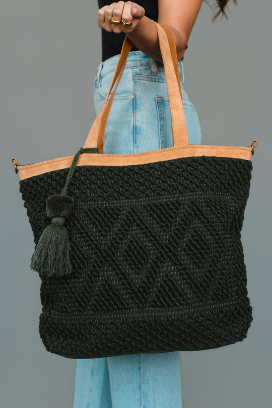 A person wearing light blue jeans and a black top holds the Panache Apparel Collection Dark Green Diamond Pattern Textured Tote.