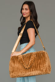 A woman in a black top and light blue jeans holds the Mustard Super Soft Ribbed Duffel by Panache Apparel Collection, a large, plush bag with a ribbed texture and gold strap, while standing against a plain gray background.