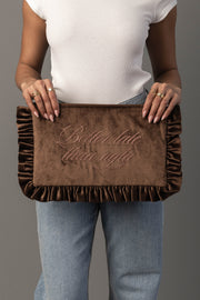 A person wearing a white shirt and jeans holds the Panache Apparel Collection Better Late Than Ugly Ruffle Travel Pouch.