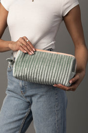 A person wearing a white ribbed shirt and blue jeans holds the Panache Apparel Collection Light Green & Orange Ribbed Travel Pouch with both hands against a gray background.
