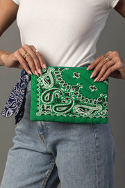 A person in a white top and jeans holds the Panache Apparel Collection Green Bandana Clutch, which has a blue bandana tied to it. They are also wearing multiple rings on their fingers.
