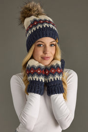 Person wearing a knit hat and mittens with a pom-pom on a gray background