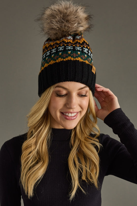 Woman wearing a patterned beanie with a pom-pom against a gray background