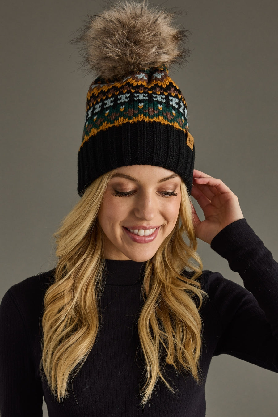 Woman wearing a patterned beanie with a pom-pom against a gray background