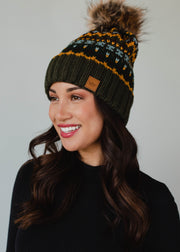 Woman wearing a patterned beanie with a pom-pom on a gray background