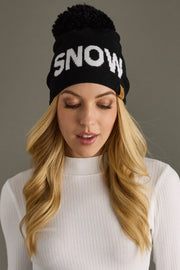 Woman wearing a black beanie with 'SNOW' text on a gray background