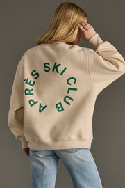 Person wearing a beige sweatshirt with green text on the back against a gray background