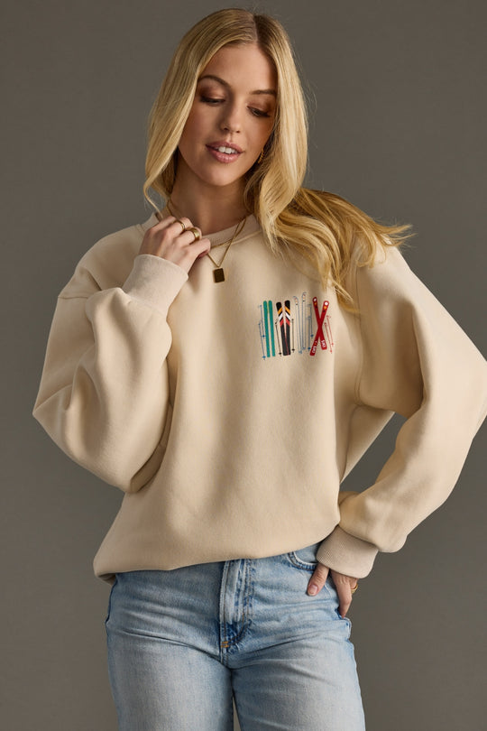 Woman wearing a beige sweatshirt with colorful text design against a gray background