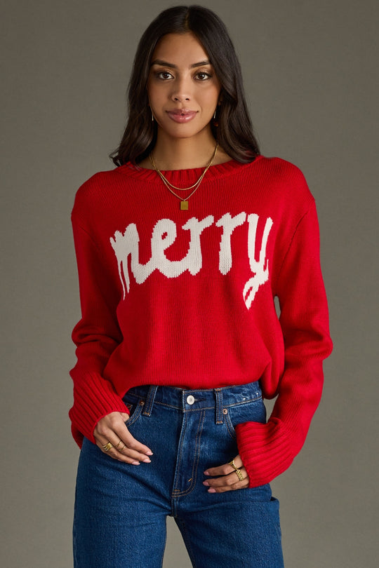 Woman wearing a red sweater with 'merry' text against a gray background