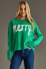 Woman wearing a green sweater with 'merry' text against a gray background