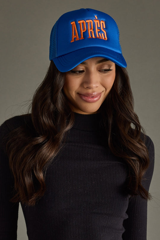 Woman wearing a blue cap with 'APRèS' text on a gray background