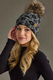 Woman wearing a patterned beanie with a pom-pom on a gray background