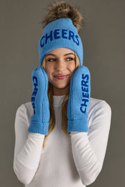 Person wearing a blue 'CHEERS' beanie and mittens against a gray background