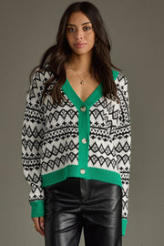 Woman wearing a patterned cardigan with green trim on a gray background