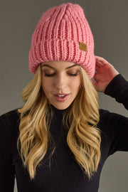 Woman wearing a pink knit beanie against a gray background