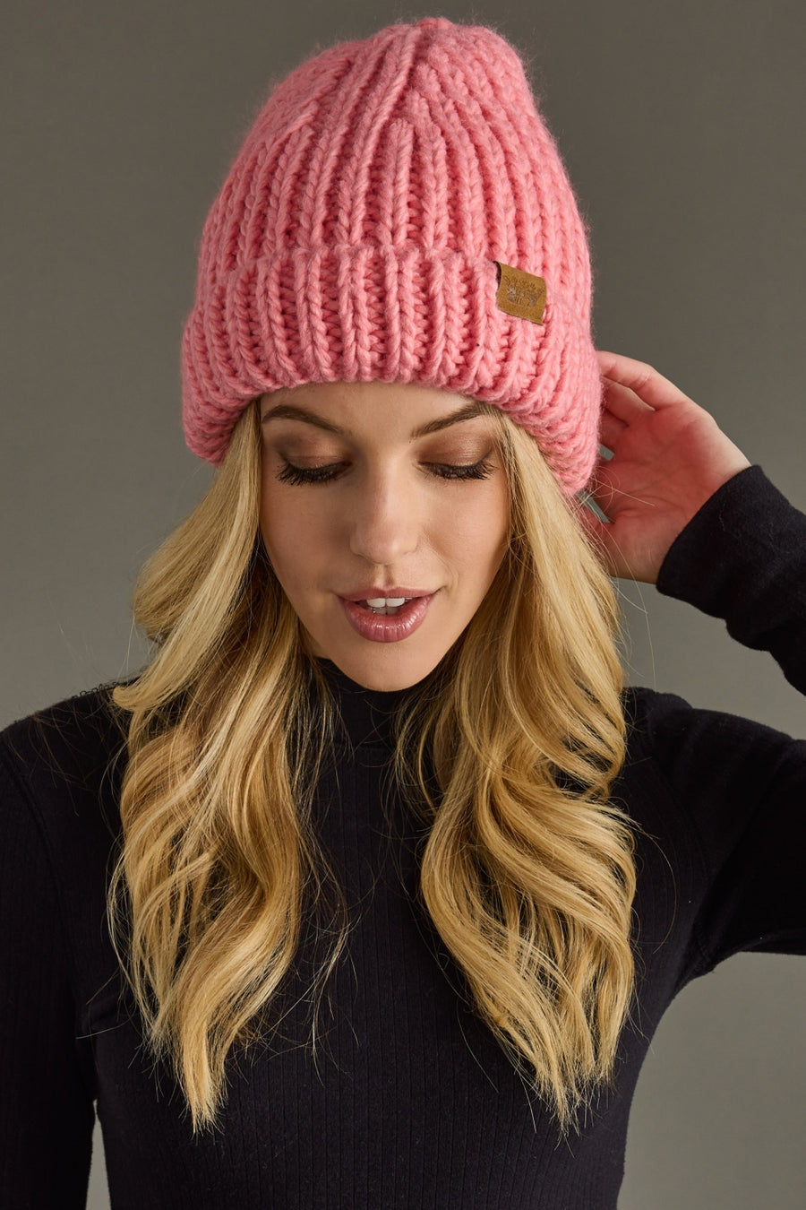 Woman wearing a pink knit beanie against a gray background