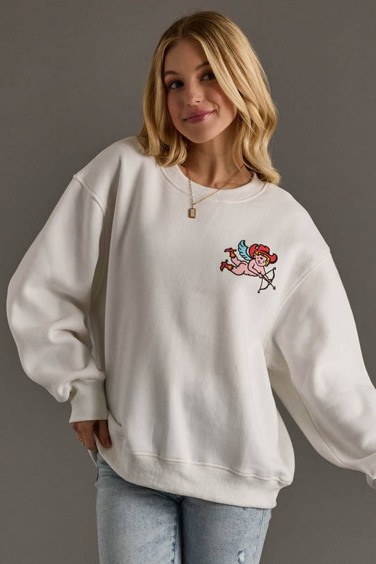 Woman wearing a white sweatshirt with a cartoon character design on a gray background