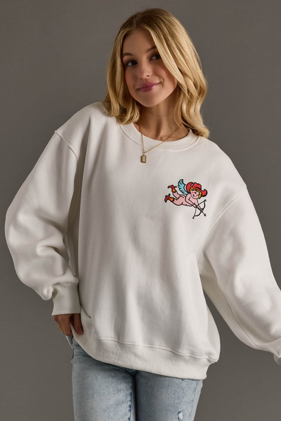 Woman wearing a white sweatshirt with a cartoon character design on a gray background