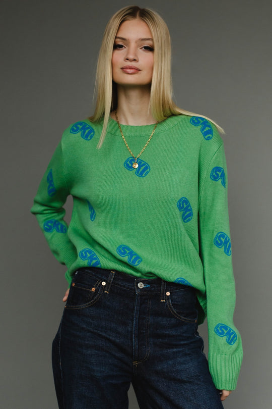 Woman wearing a green sweater with blue patterns against a gray background