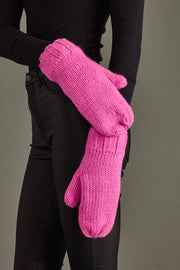 Person wearing bright pink knitted mittens against a neutral background