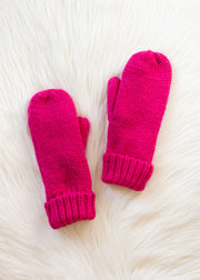 Pair of bright pink mittens on a white fur surface