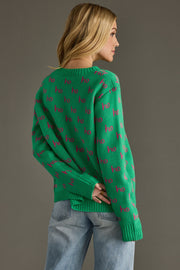 Person wearing a green sweater with pink patterns on a gray background