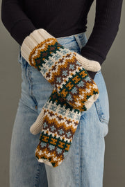 Person wearing patterned mittens with a plain background