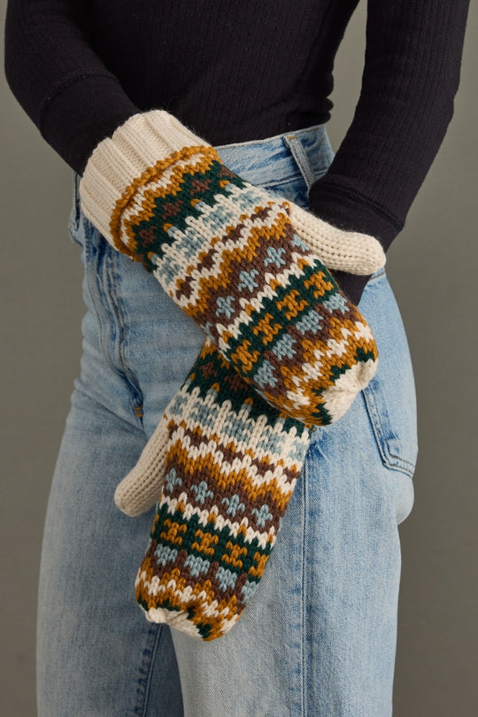 Person wearing patterned mittens with a plain background