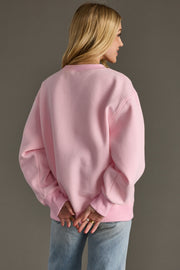 Person wearing a pink sweatshirt and blue jeans against a gray background