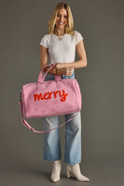 Woman holding a pink bag with 'merry' written on it against a gray background