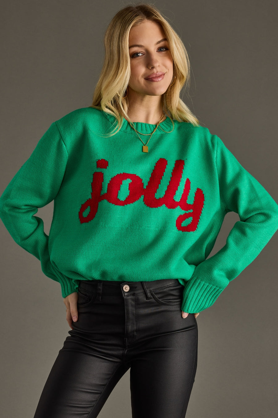 Woman wearing a green sweater with 'jolly' in red text against a gray background