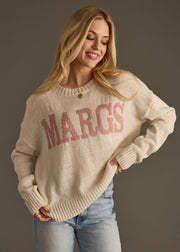 Woman wearing a beige sweater with 'MARCIS' text on a plain background