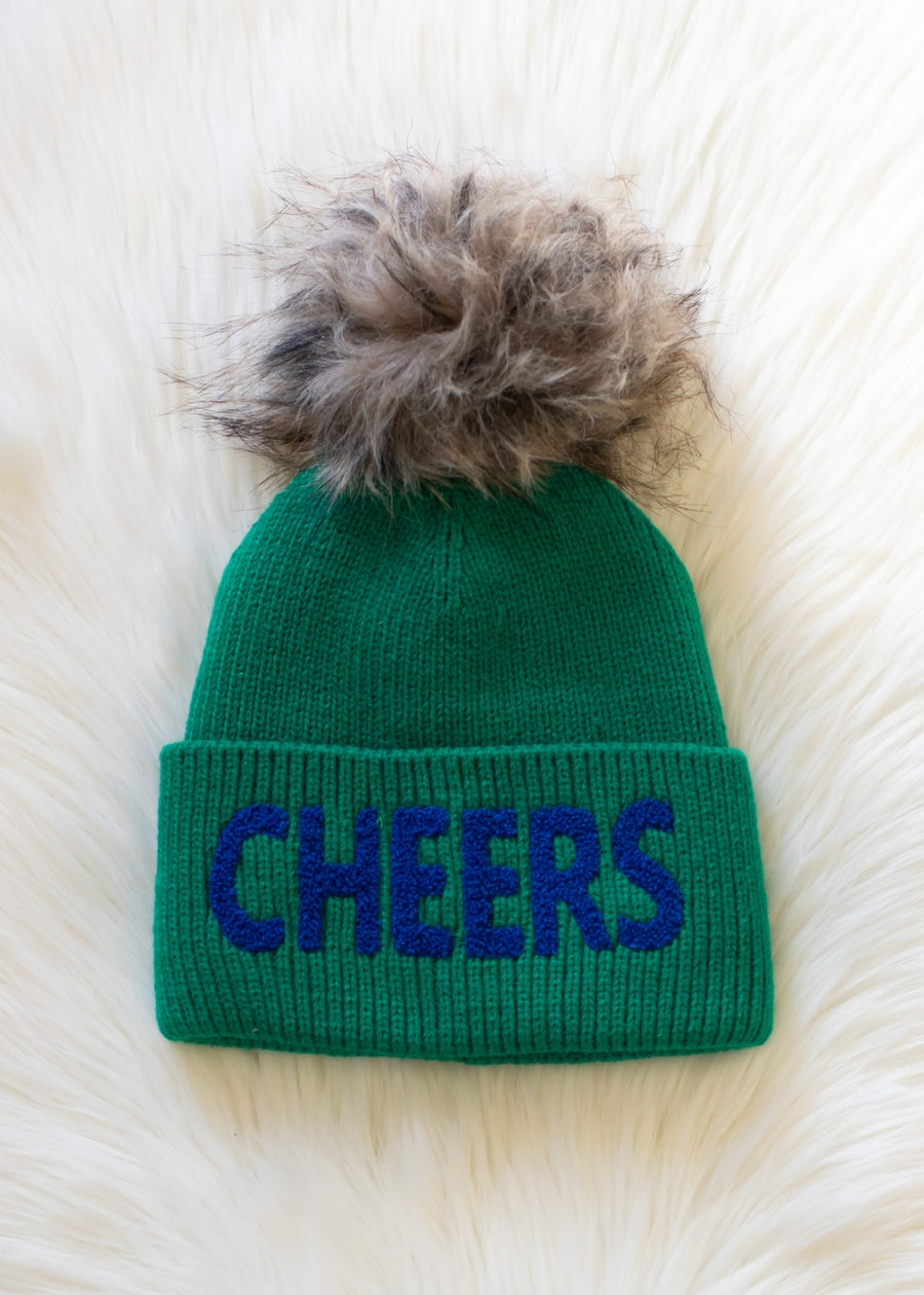 Green beanie with 'CHEERS' text and fur pom-pom on a white background