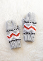Pair of gray knitted mittens with red and white pattern on a fluffy white surface