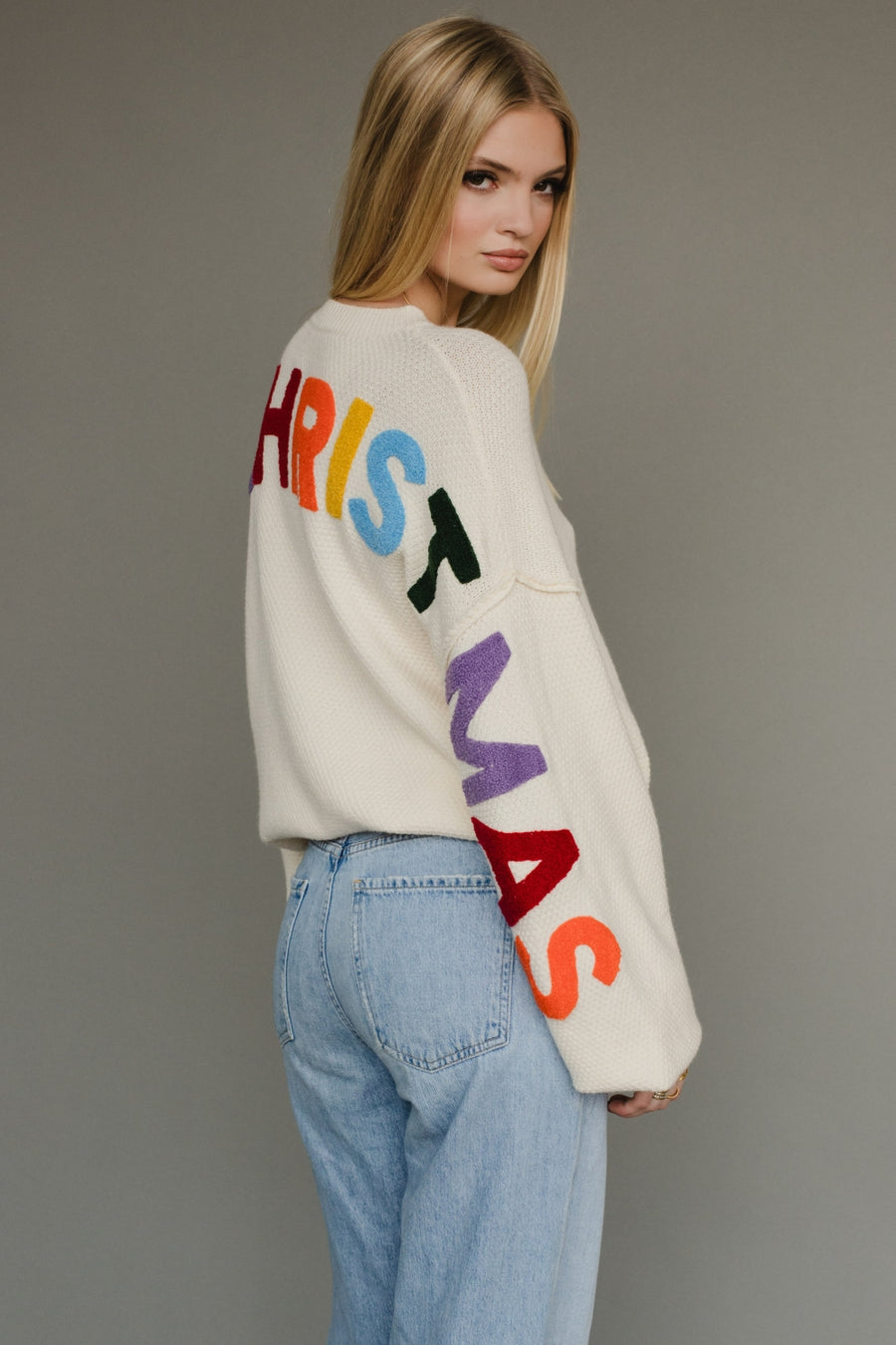 Ivory knit sweater with multicolored 'Merry Christmas' text on the back